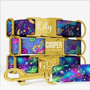 May include: Three pet collars with gold-tone metal buckles and hardware. The fabric features a colorful space pattern with planets, stars, and rockets. The buckles are engraved with the names Lily, COOPER with 123-456-7890, and GUS.