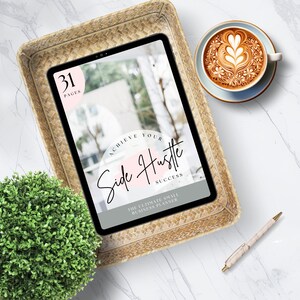 Puede incluir: Una tableta mostrando un planificador digital con el texto "Achieve Your Side Hustle Success" y "The Ultimate Small Business Planner". La tableta est&aacute; en una cesta tejida sobre una superficie de m&aacute;rmol blanco con una taza de caf&eacute; y un bol&iacute;grafo.
