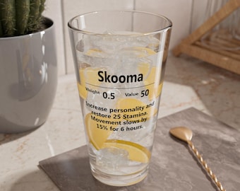 May include: A clear glass filled with ice, lemon slices, and a beverage. The glass has text that reads "Skooma", "Weight 0.5", and "Value 50". The text also describes the effects of the drink. A gold-colored spoon rests on the counter.