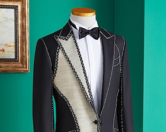 Puede incluir: Una chaqueta de esmoquin negra con camisa blanca y pajarita negra. La chaqueta tiene un diseño único con un panel blanco en la parte delantera que está delineado con costuras blancas.