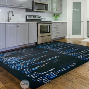 May include: A black and blue rug with code printed on it. The rug is in a kitchen with white cabinets and a stainless steel oven.