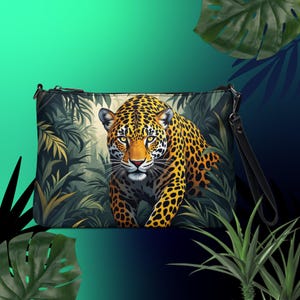 May include: A black clutch bag with a zipper closure and a long black strap. The front of the bag features a colorful illustration of a jaguar walking through a jungle scene.
