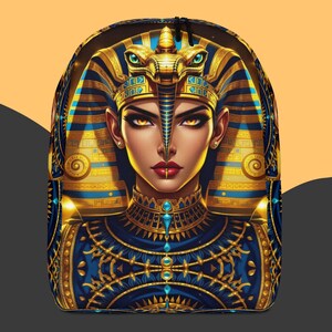 May include: A backpack with a detailed illustration of an Egyptian pharaoh. The design features a blue and gold colour scheme, with intricate patterns and a central portrait of a regal figure. The backpack has a black zip and straps.