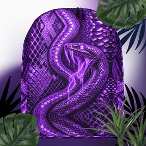 Puede incluir: Una mochila de cordón con un gráfico de serpiente de color morado vibrante con un patrón de escamas detallado. La serpiente se muestra con la boca abierta, revelando colmillos y un ojo brillante en toda la superficie frontal.