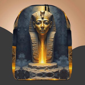 May include: A backpack with a detailed golden bust of an Egyptian pharaoh. The pharaoh's face is highlighted with gold, set against a dark, textured backdrop. A bright light emanates from the pharaoh's chest, creating a dramatic effect. The design is eye-catching.