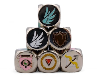 Puede incluir: Un conjunto de seis dados de metal plateado con diferentes diseños de colores y patrones. Los dados presentan un escudo, alas, una luna creciente, un triángulo, un arco y una flecha, y un ojo.