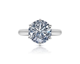 May include: A silver ring with a large, round, clear diamond.
