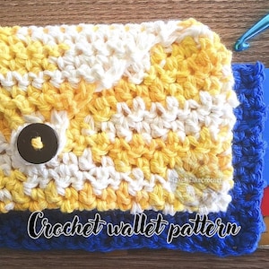 May include: A rectangular crochet wallet featuring a yellow and white variegated yarn flap secured by a dark brown button, layered over a solid blue crochet base. The wallet contains several credit cards and a one-dollar bill, with a blue crochet hook nearby.