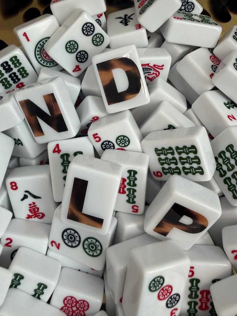 May include: A collection of white rectangular Mahjong tiles featuring various green and red symbols, numbers, and characters. Three prominent tiles are printed with the large black letters N, D, and L, each featuring a brown leopard print pattern.
