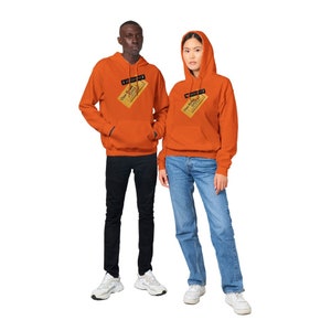 May include: Two people wearing orange hoodies with a yellow ticket design on the front. The ticket says "One-Way Ticket to the City".
