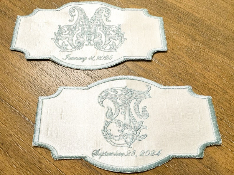 May include: Two embroidered patches with a light blue border and script. One patch features the letters "AM" and the date "January 11, 2025." The other patch has the letters "TF" and the date "September 28, 2024."