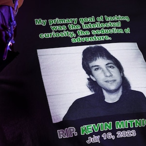 Könnte beinhalten: Ein schwarzes T-Shirt mit einem Foto von Kevin Mitnick und dem Text "My primary goal of hacking was the intellectual curiosity, the seduction of adventure." und "RIP. KEVIN MITNIC July 16, 2023".