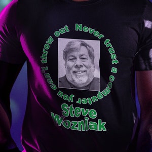 Könnte beinhalten: Ein schwarzes T-Shirt mit einem grünen Kreis-Motiv, das ein Porträt von Steve Wozniak und den Text "Vertraue niemals einem Computer, den du nicht wegwerfen kannst" zeigt.