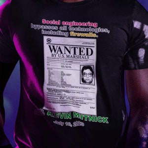 Peut inclure: Un t-shirt noir avec un graphique blanc d'un avis de recherche pour Kevin Mitnick. L'affiche comprend le texte "Social engineering bypasses all technologies, including firewalls." et "WANTED BY U.S. MARSHALS". L'affiche comprend également une photo de Kevin Mitnick et la date "July 10, 2029".