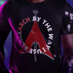 Puede incluir: Una persona con una camiseta negra con un diseño gráfico rojo y blanco que dice "Use the Way Blackarch By". La persona lleva gafas de color verde neón y tiene rastas.