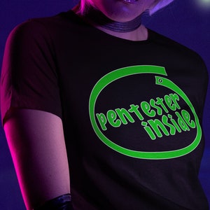 May include: A person wearing a black t-shirt with a green circle graphic that says "pentester inside".