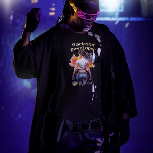 K&ouml;nnte beinhalten: Eine Person tr&auml;gt ein schwarzes T-Shirt mit einer bunten Grafik, auf der "Backend Developer" und ein Python-Logo stehen. Die Person tr&auml;gt eine rosa Brille und hat Dreadlocks.