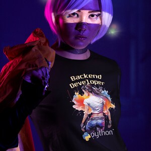 K&ouml;nnte beinhalten: Ein schwarzes T-Shirt mit einer bunten Grafik einer stehenden Frau mit dem Text "Backend Developer" und einem Python-Logo. Der Text "python" befindet sich unter dem Logo.
