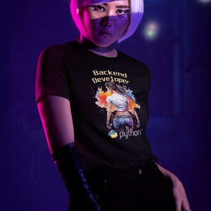 K&ouml;nnte beinhalten: Ein schwarzes T-Shirt mit einer bunten Grafik einer Frau mit dem Text "Backend Developer" und "python" darauf.