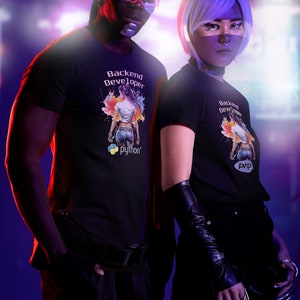 K&ouml;nnte beinhalten: Zwei Personen tragen schwarze T-Shirts mit einer bunten Grafik einer Frau und dem Text "Backend Developer" mit den Logos f&uuml;r Python und PHP.