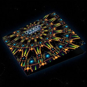 Może przedstawiać: Czarne etui na płytę CD z kolorowym, psychodelicznym wzorem przedstawiającym okrągły wzór w kolorze żółtym, pomarańczowym, zielonym i niebieskim. Na etui nadrukowany jest tekst "Omneon Ascension".