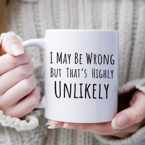 May include: White ceramic coffee mug with black text that reads "I may be wrong but that's highly unlikely".