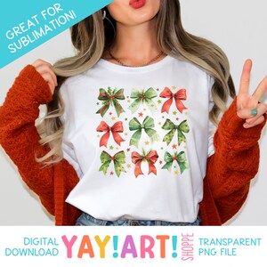 K&ouml;nnte beinhalten: Ein wei&szlig;es T-Shirt mit einem Design aus mehreren roten und gr&uuml;nen Aquarell-Schleifen mit goldenen Sternen. Der Text "YAY!ART!" befindet sich am unteren Rand des Bildes.
