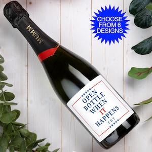 May include: A dark glass Mumm champagne bottle with a custom white label featuring a red border and blue text that reads OPEN BOTTLE WHEN IT HAPPENS FDT with stars. A blue starburst graphic in the corner displays the text CHOOSE FROM 6 DESIGNS.
