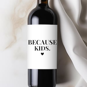May include: A dark glass wine bottle with a white label. The label reads "BECAUSE KIDS." in a bold, black font, with a small black heart below the text. The bottle is filled with red wine.