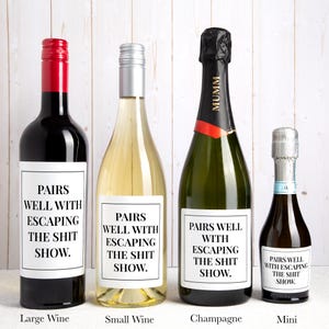 May include: Four bottles of varying sizes, including a large wine bottle with a red cap, a small wine bottle with a silver cap, a champagne bottle with a black foil top, and a mini bottle, each featuring a white label with the text PAIRS WELL WITH ESCAPING THE SHIT SHOW.