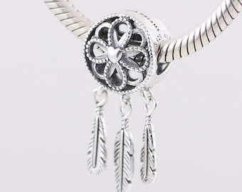 May include: Silver charm with a dreamcatcher design featuring a circle with a flower and three feathers hanging from it. The charm has the text "Sweet Dreams" engraved on it.