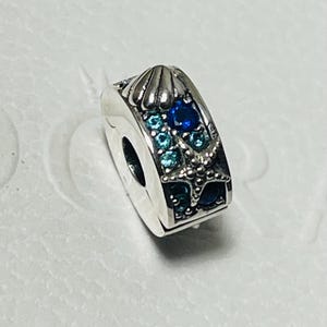 May include: Silver charm bracelet clip with a blue and turquoise seashell and starfish design.