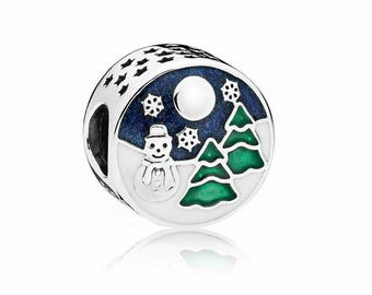 May include: A silver charm with a blue and white enamel design of a snowman and two green trees against a starry night sky.