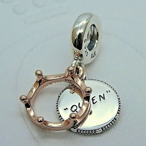 May include: A silver charm with a rose gold crown and a silver disc that says "Queen" on it.