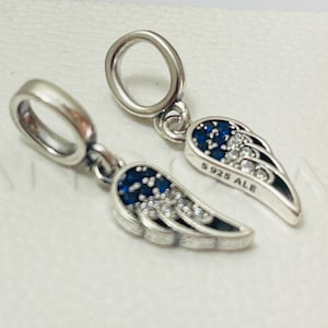 May include: Two silver charm pendants in the shape of angel wings with blue and white crystals. The back of one pendant is stamped with "S925 ALE".