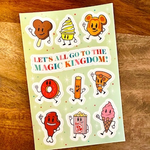 Może przedstawiać: Zestaw 10 kolorowych naklejek przedstawiających różne artykuły spożywcze z motywem Disneya, w tym uszy Myszki Miki, gałki lodów, wiaderka popcornu i churrosy. Naklejki znajdują się na zielonym tle z białymi kropkami i tekstem "Let's all go to the Magic Kingdom!" w kolorach tęczy.