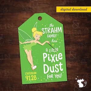 Puede incluir: Una etiqueta verde con el personaje de Campanilla y el texto "the STRAHM FAMILY has a little PIXIE DUST FOR YOU!" y "STATEROOM 9128". La etiqueta tiene un agujero en la parte superior y una etiqueta de descarga digital.
