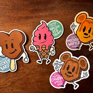 May include: Four colorful stickers featuring Mickey Mouse-themed ice cream treats. The stickers feature Mickey Mouse's head with different ice cream flavors, including a chocolate bar, a waffle cone, a churro, and a waffle. Each sticker has a fun slogan related to the ice cream treat.