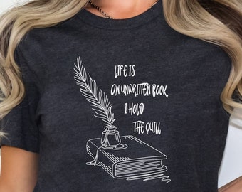 May include: Dark gray heather t-shirt with a white graphic of a quill pen, inkwell, and an open book. The text on the shirt reads "Life is an unwritten book, I hold the quill."