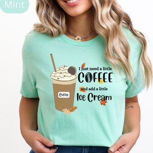 May include: Mint green t-shirt featuring a coffee drink graphic with whipped cream, a cookie, and a straw. The text reads "I just need a little coffee and add a little ice cream" with fall leaf accents. The word "Coffee" is also printed on the cup.