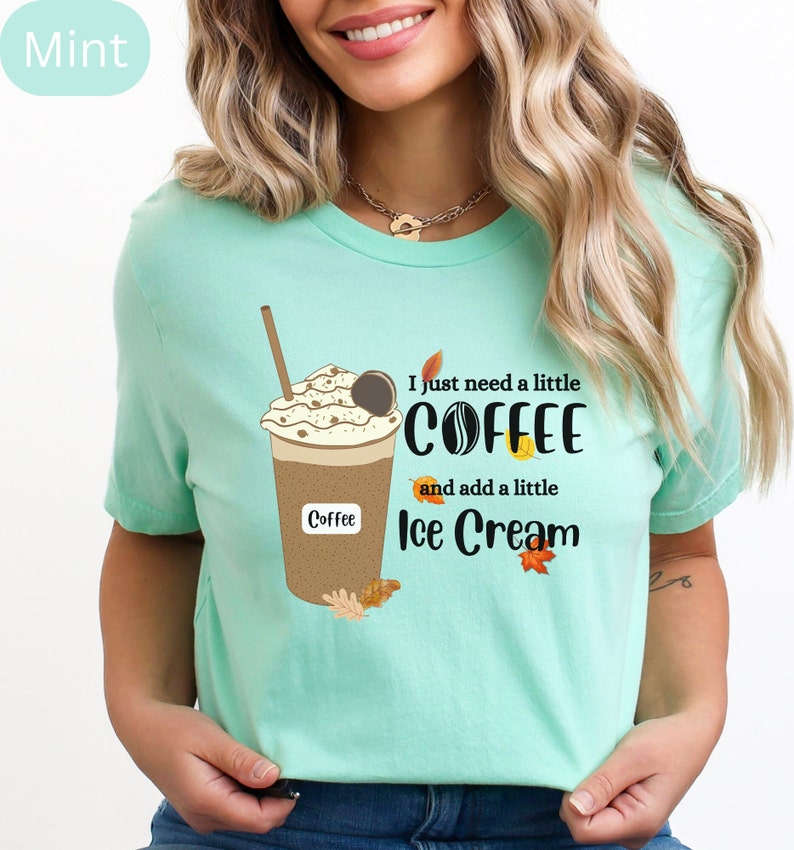 May include: Mint green t-shirt featuring a coffee drink graphic with whipped cream, a cookie, and a straw. The text reads "I just need a little coffee and add a little ice cream" with fall leaf accents. The word "Coffee" is also printed on the cup.