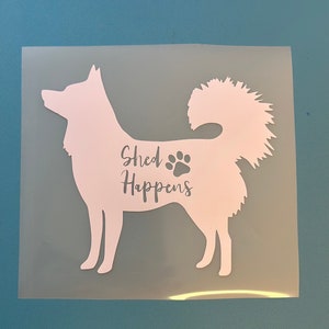 May include: White silhouette of a dog with a fluffy tail. The dog is facing left and the text "Shed Happens" is written on the dog's body with a paw print.