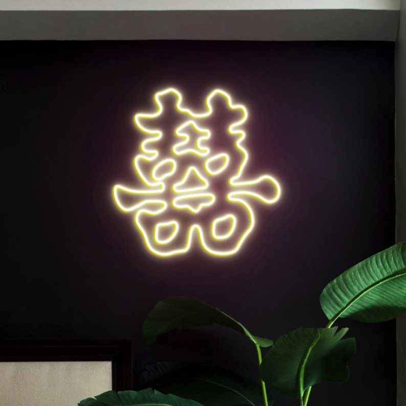 May include: A yellow neon sign on a dark wall with the Chinese character for "double happiness" in a stylised font.
