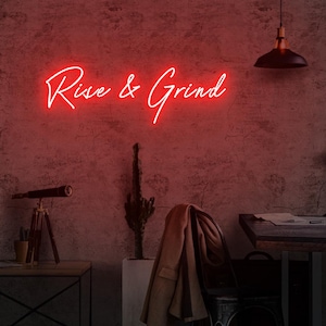 Puede incluir: Un letrero de neón rojo que muestra las palabras "Rise & Grind" en una fuente cursiva, montado en una pared texturizada de color marrón rojizo. La escena incluye un telescopio, un cactus en maceta y un abrigo.