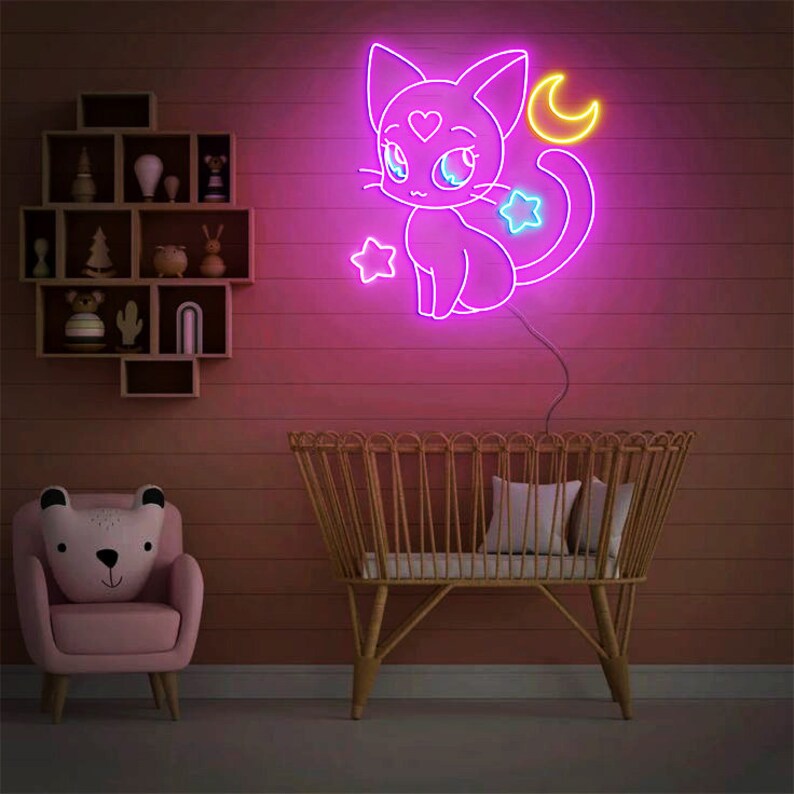 May include: A pink neon sign of a cartoon cat with a heart on its chest and a crescent moon above its head. The cat has blue eyes and a star on its tail. The sign is lit up and is hanging on a pink wall.