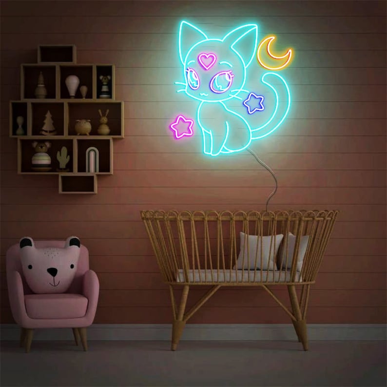 May include: A neon sign depicting a blue cat with a pink heart on its forehead, a yellow crescent moon, and purple stars. The sign is mounted on a pink wall above a wicker crib.