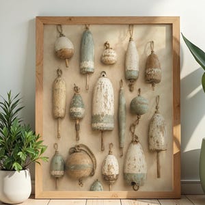 May include: A framed wall art piece featuring a collection of weathered, vintage-style fishing buoys in various shapes and sizes. The buoys are painted in muted shades of white, blue, and brown, showing distressed textures and attached rope loops.