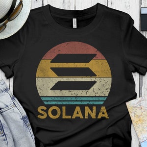 May include: Black t-shirt with a vintage-style graphic of the Solana logo. The logo is a stylized letter "S" with a sunset-colored background. The text "SOLANA" is printed below the logo.