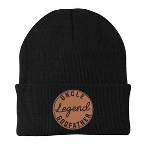 May include: Black beanie with a brown leather patch. The patch has the words "UNCLE Legend GODFATHER" in a circular design. The beanie is made of a soft, knitted material.