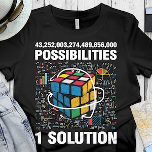 May include: Black t-shirt with a colorful Rubik's Cube graphic and the text "43,252,003,274,489,856,000 POSSIBILITIES 1 SOLUTION".